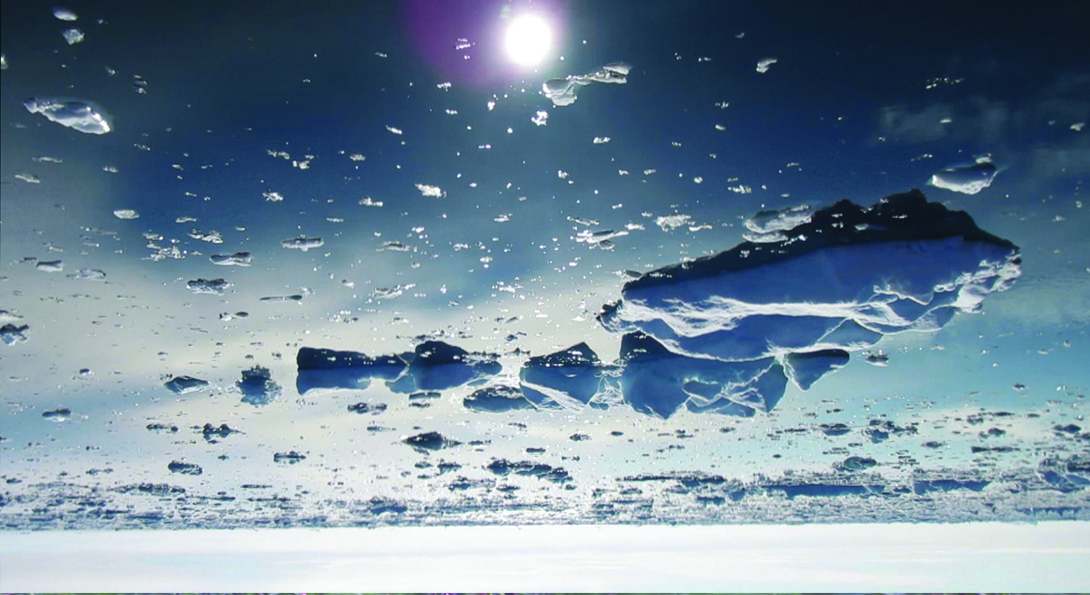 An upside-down photograph of melting glaciers in water. A white